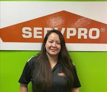 Woman standing in front of a green background with SERVPRO logo. 