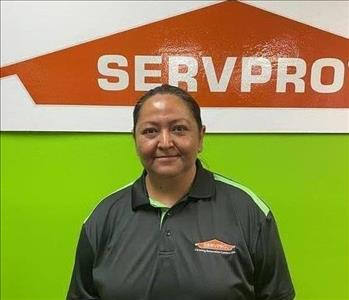 Woman standing in front of a green wall with orange SERVPRO logo
